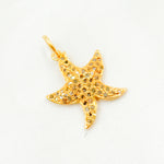 Load image into Gallery viewer, A gold-plated starfish pendant with diamond accents on a white background.