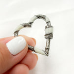 Load image into Gallery viewer, A sterling silver heart-shaped carabiner clasp with black rhodium and gold plating, held between fingers.