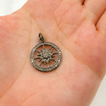 Load image into Gallery viewer, A hand holding a sterling silver round sun pendant with black rhodium and rose gold plating, encrusted with small diamonds.
