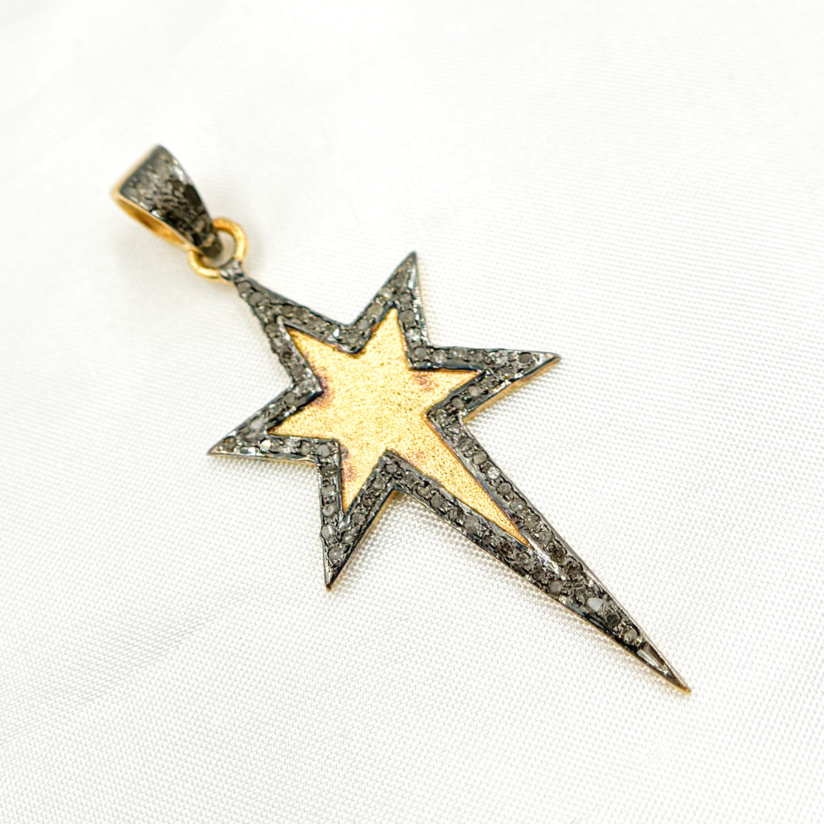 A set of three star-shaped diamond pendants in different finishes: one with black rhodium, one gold-plated, and one rose gold-plated, displayed against a white background.