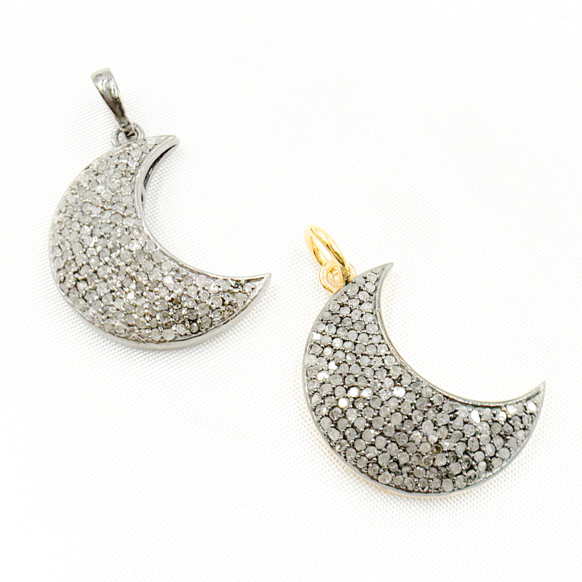 Two diamond-studded sterling silver moon pendants with black rhodium and gold plating, displayed against a white background.