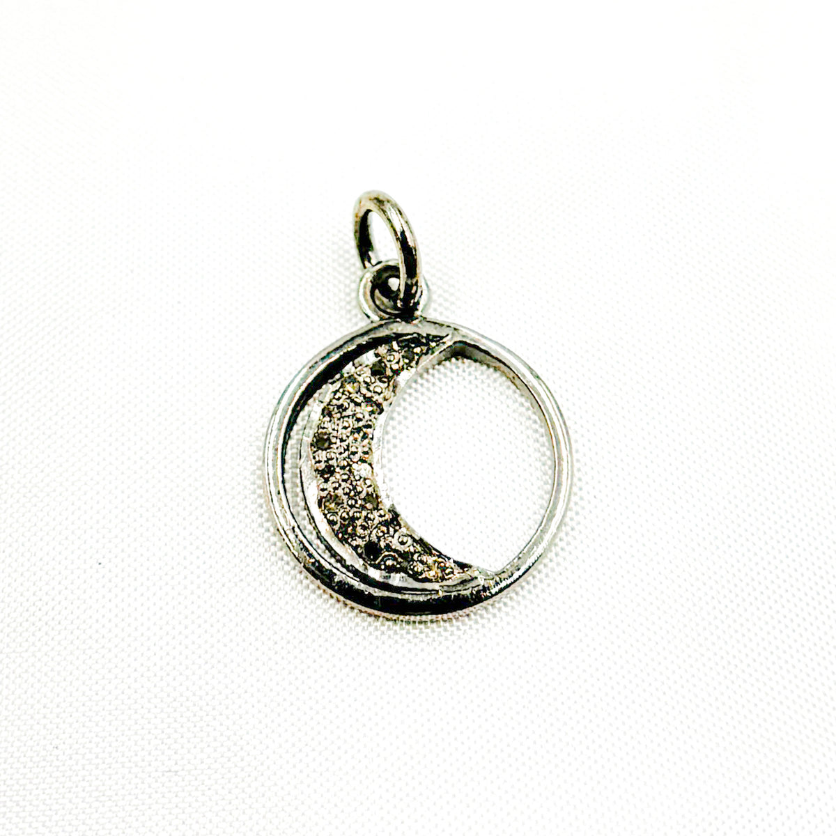 A selection of round moon charms in different finishes: silver with black rhodium, gold plated, and rose gold plated, each featuring a patterned interior.