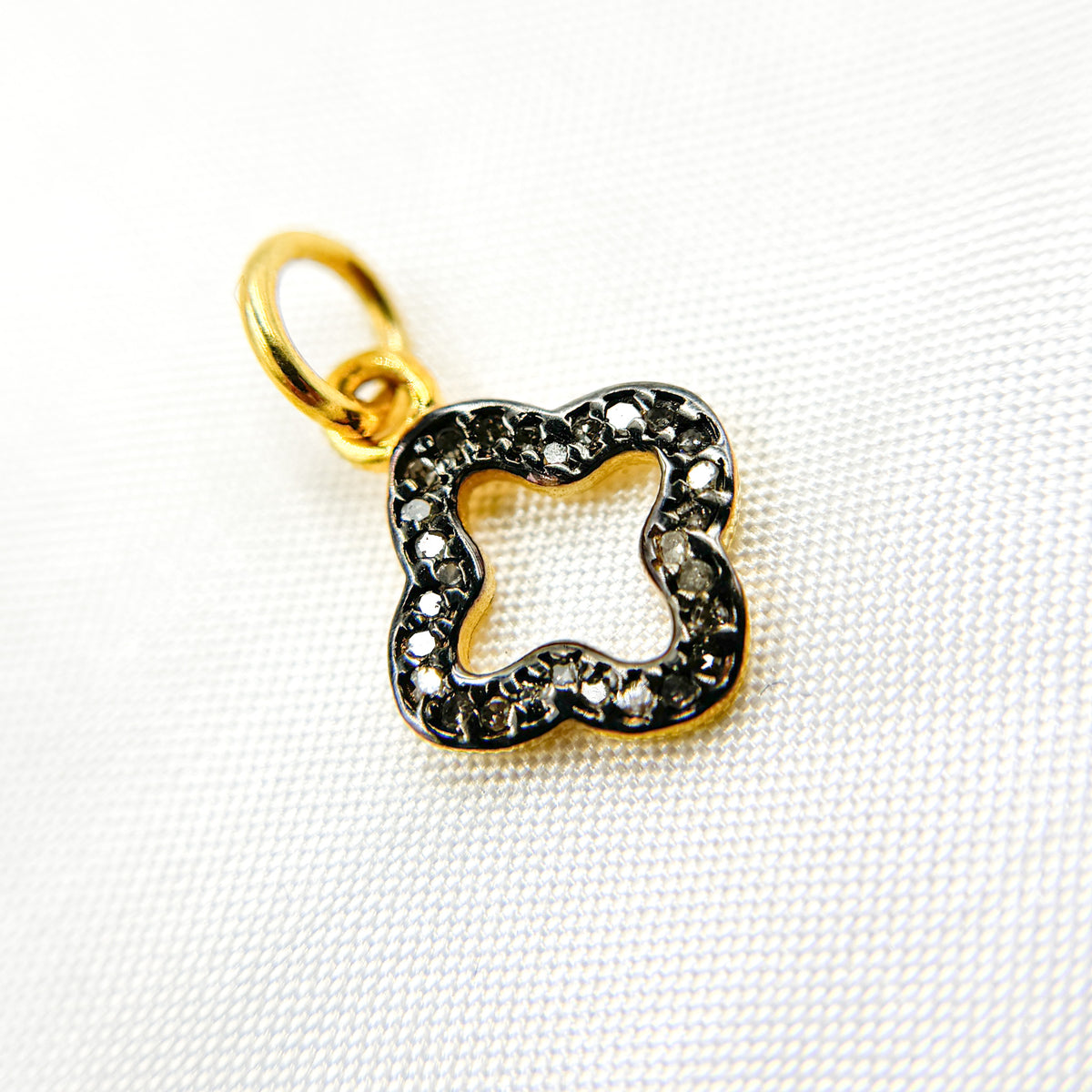 diamond sterling silver flower charms, one with black rhodium plating, one gold plated, and one rose gold plated, displayed against a white background.